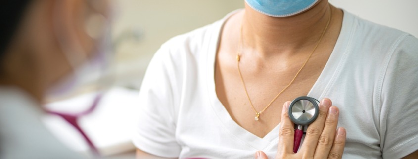 médica escuta o pulmão de paciente sentada
