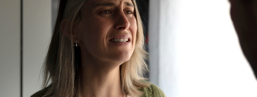 pessoa com expressão de dor encostada na parede demonstrando angústia