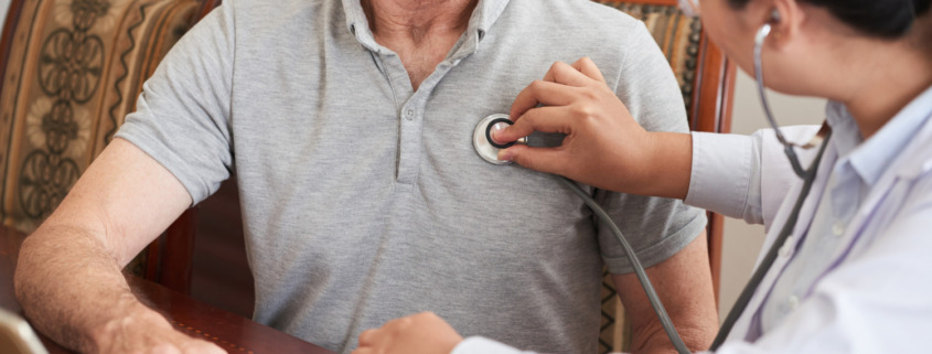 médico avaliando coração de paciente em ambiente residencial, demonstrando cuidados básicos