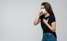 pessoa com máscara de proteção no rosto tossindo, indicando problemas respiratórios
