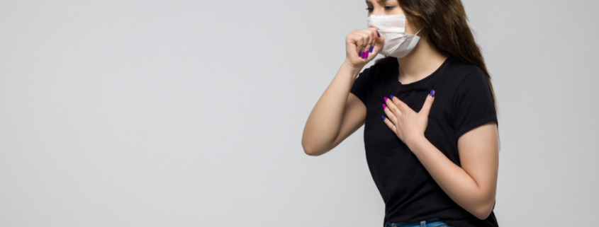 pessoa com máscara de proteção no rosto tossindo, indicando problemas respiratórios