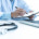 médico em consultório utilizando notebook e preenchendo documentos