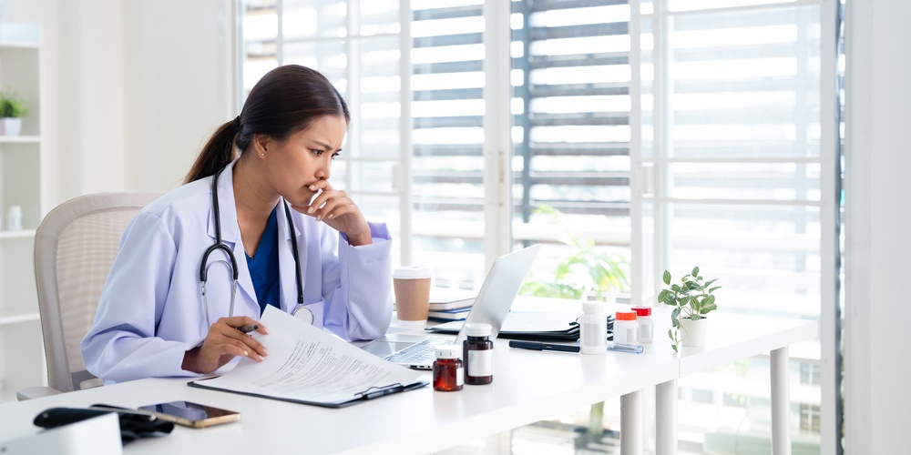 médica em consultório médico analisando arquivo no notebook