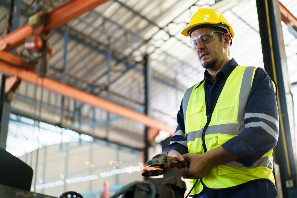 operário atuando com maquinário em área industrial