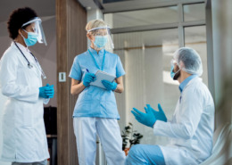 profissionais de saúde utilizando EPIs e demonstrando estar discutindo sobre casos clínicos