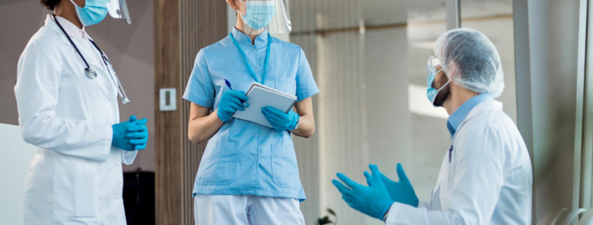profissionais de saúde utilizando EPIs e demonstrando estar discutindo sobre casos clínicos