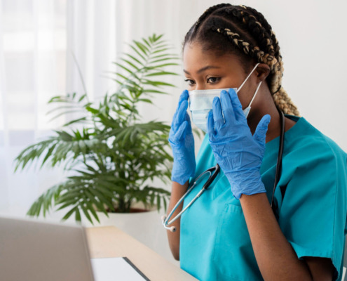 médica em consultório, observando prontuário e informações no notebook