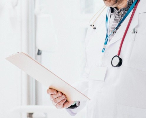 médico em consultório avaliando documento em mãos