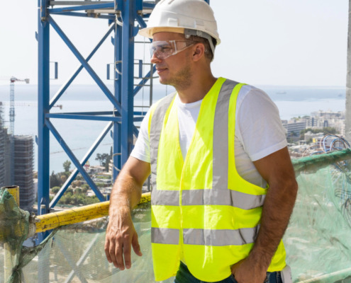 funcionário com EPIs apoiado em plataforma alta olhando para o horizonte