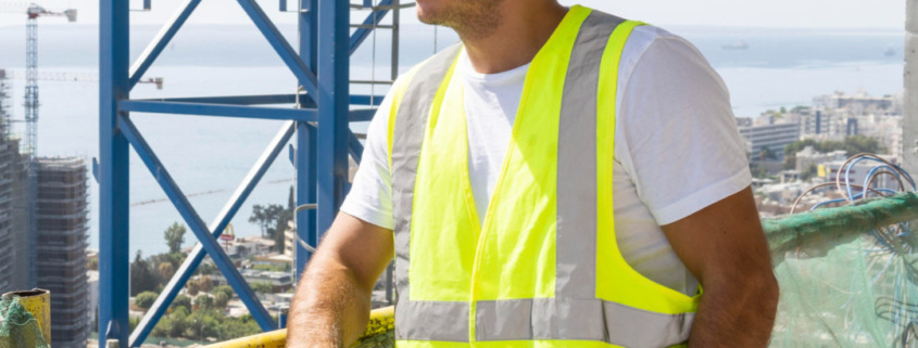 funcionário com EPIs apoiado em plataforma alta olhando para o horizonte