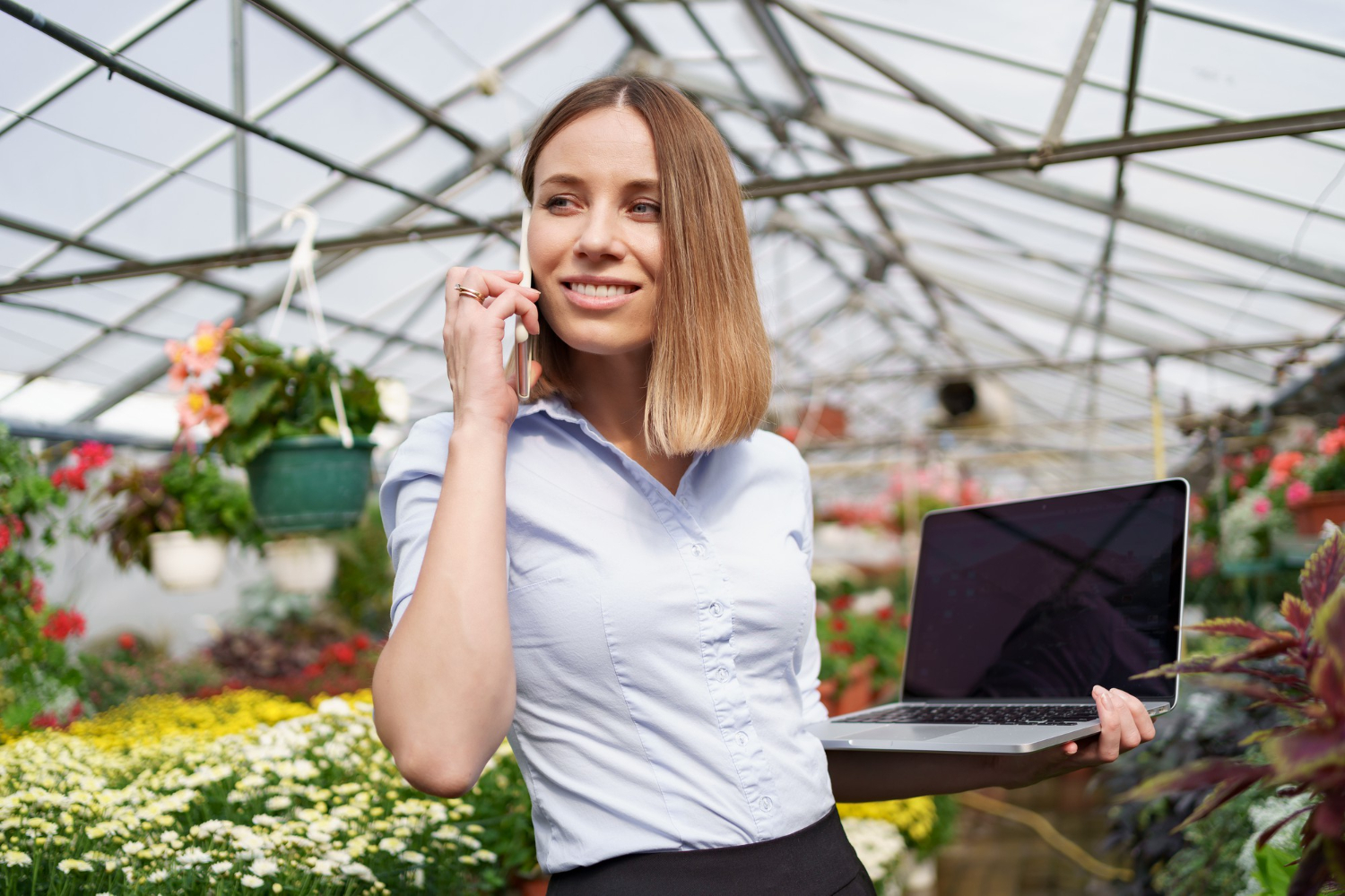 pessoa com notebook e celular em área verde simbolizando teleatendimento