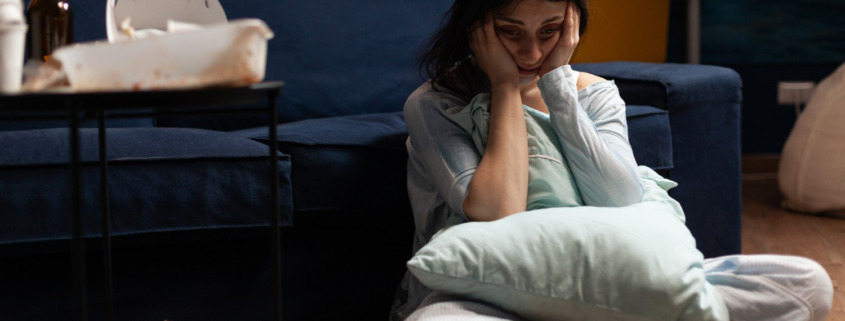 pessoa triste sentada no chão da sala com depressão