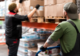 trabalhadores em galpão logístico manipulando caixas de estoque
