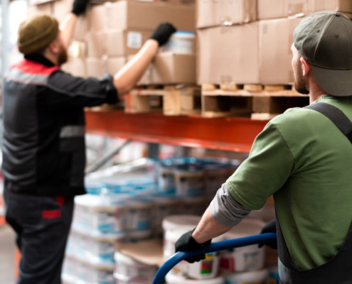 trabalhadores em galpão logístico manipulando caixas de estoque