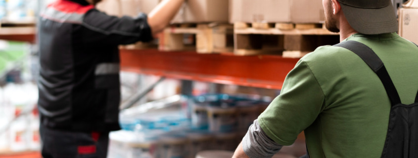 trabalhadores em galpão logístico manipulando caixas de estoque