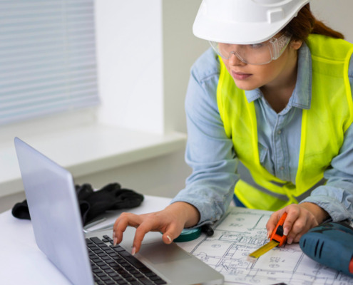 engenheira utilizando EPIs e mexendo em notebook indicando análise de obra