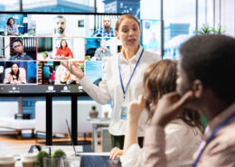 gestora em sala de reunião conduzindo conversa com pessoas presentes e online