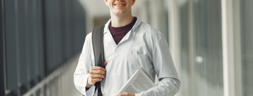 estudante de medicina sorrindo em área externa de faculdade